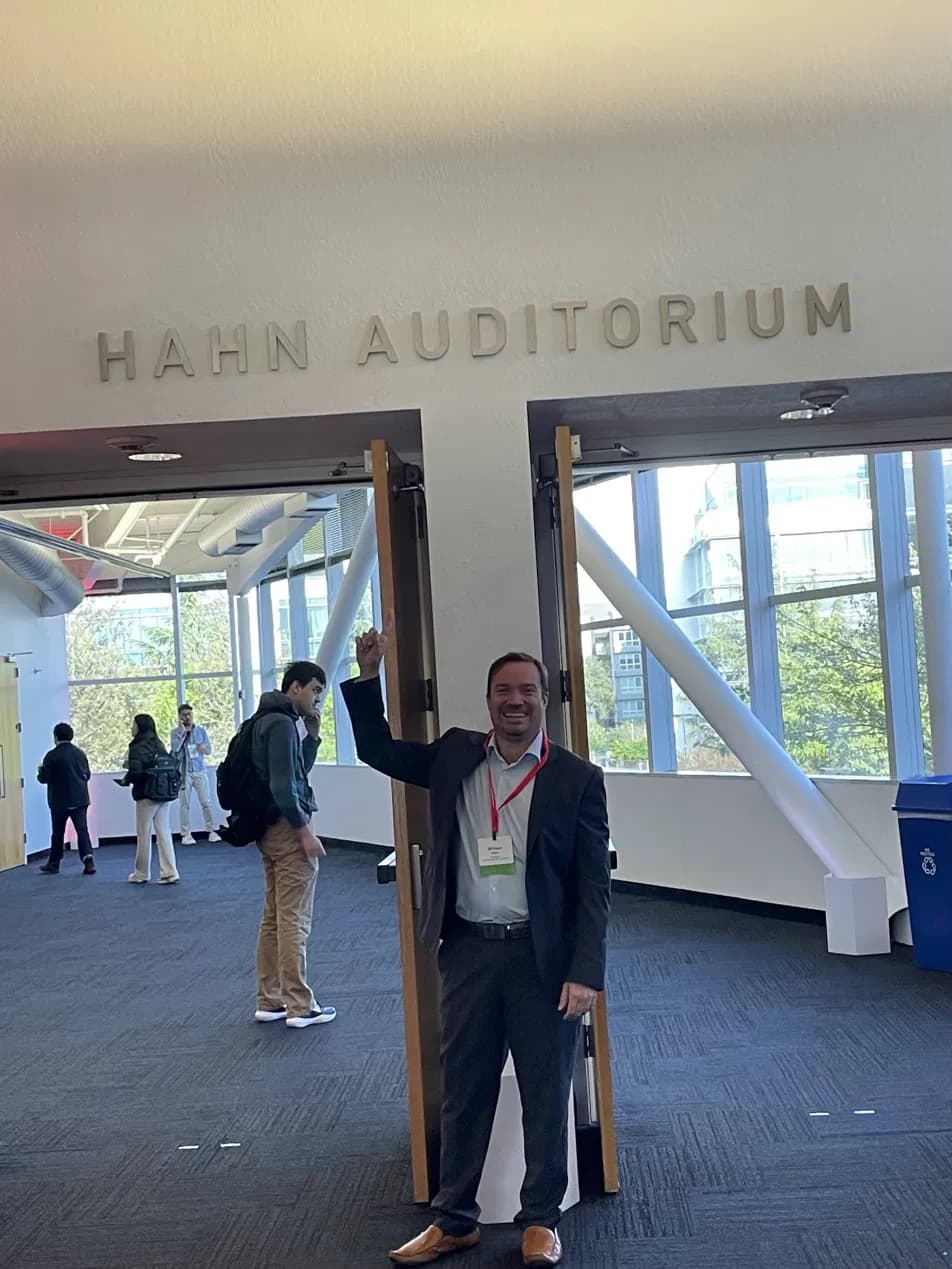 Dr. William Hahn pointing up at the Hahn Auditorium sign