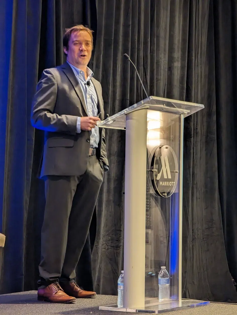 Dr. William Hahn speaking from the podium at a conference held at a Marriott hotel