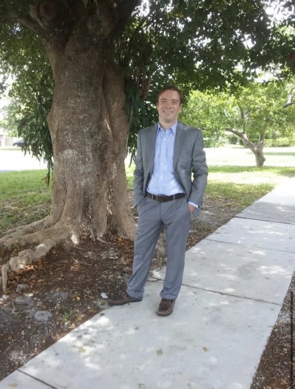 Dr. William Hahn, PhD, standing outdoors in a gray suit